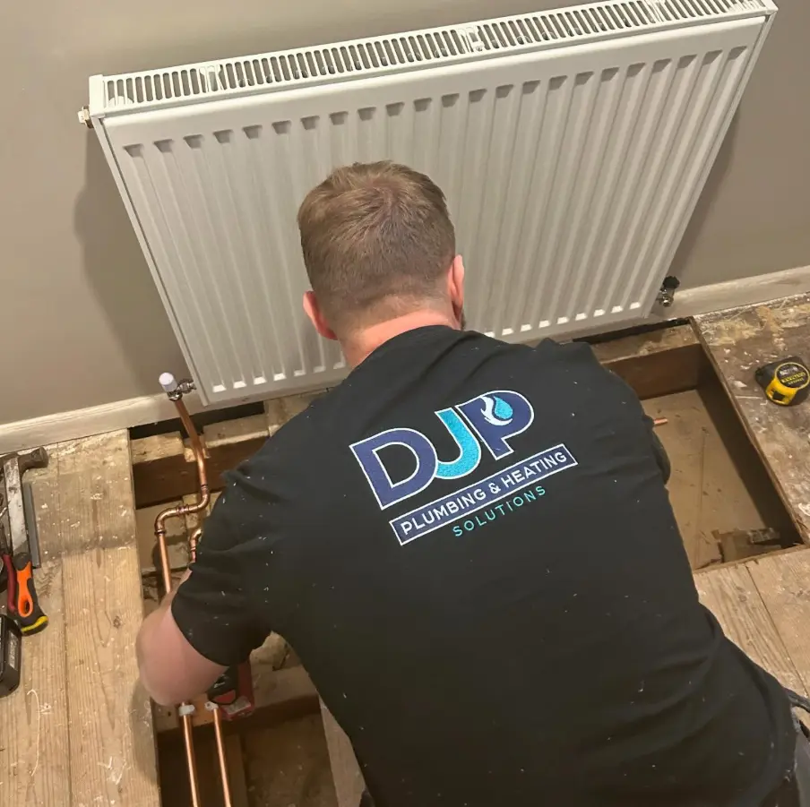 A plumber fitting a radiator on a residential job
